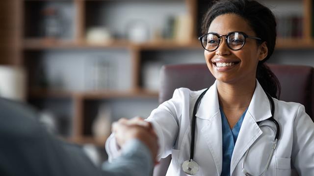 A doctor shakes hands with her patient. 