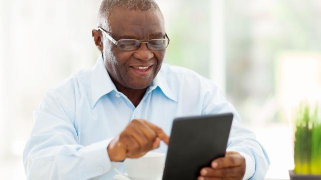 A man smiles while using a tablet.
