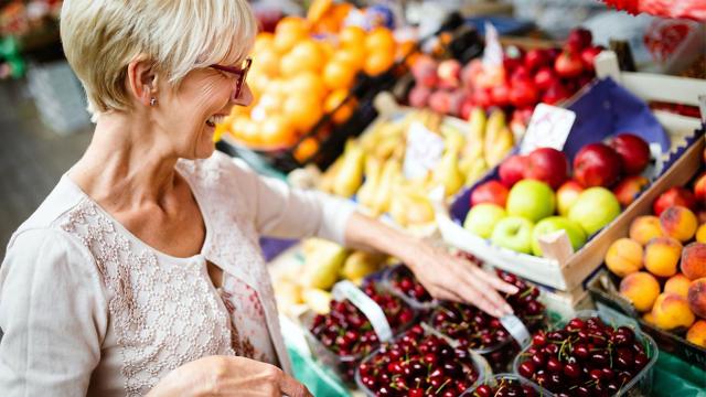 A woman chooses cherries in a grocery store. 