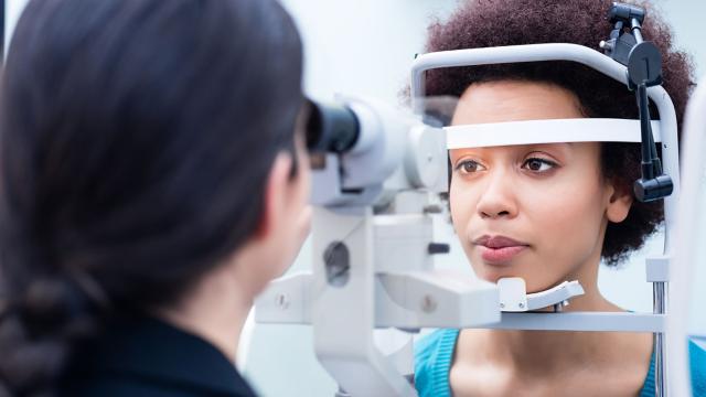 Eye doctor inspects woman’s eyes during eye exam.