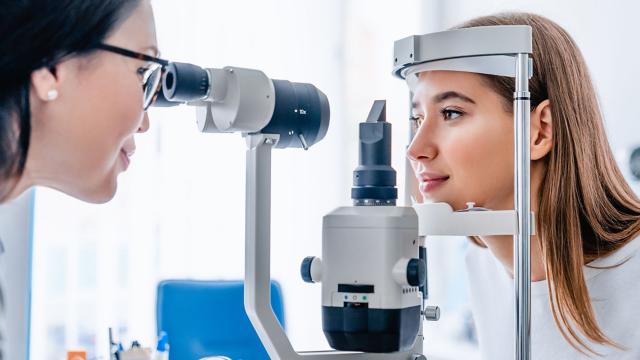 An eye doctor inspects a woman’s eyes during an exam.