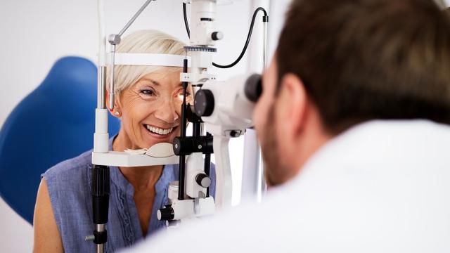 An eye doctor inspects a woman’s eye with an ophthalmoscope.