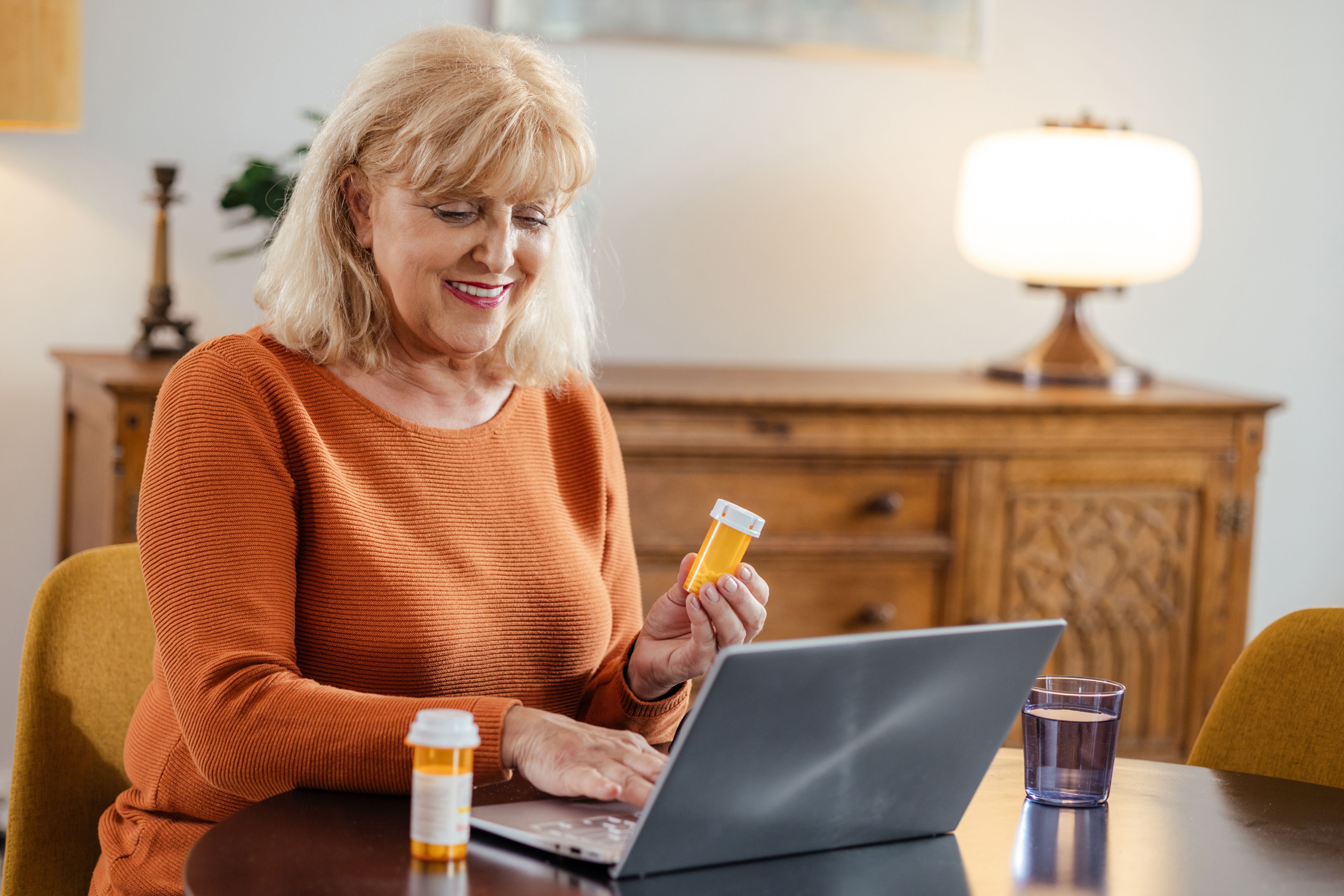 Senior woman using laptop to manage prescription medication online.