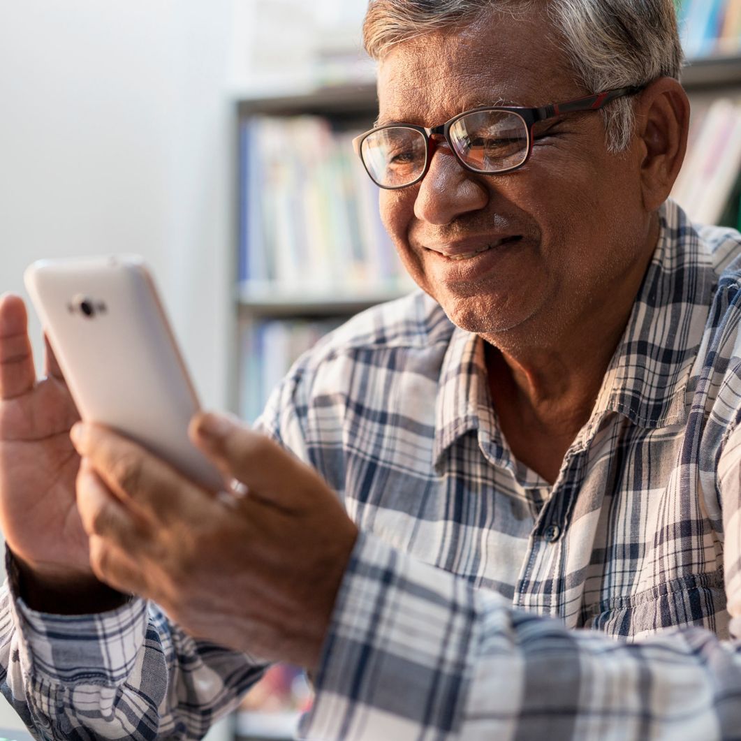 A man smiles as he reads information on his smartphone. 