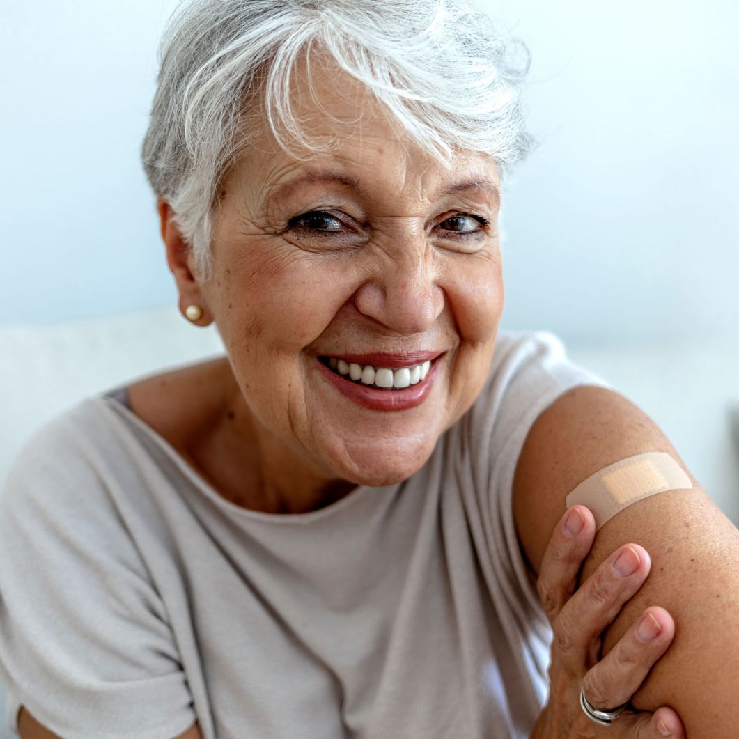 A woman smiling with a band aid on her arm.