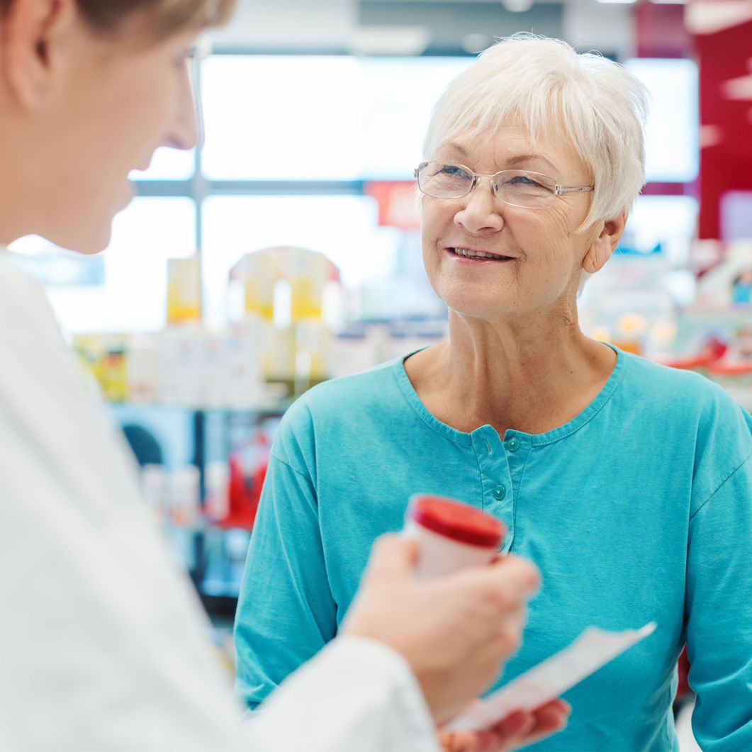 A woman listens while her pharmacist explains prescription information. 