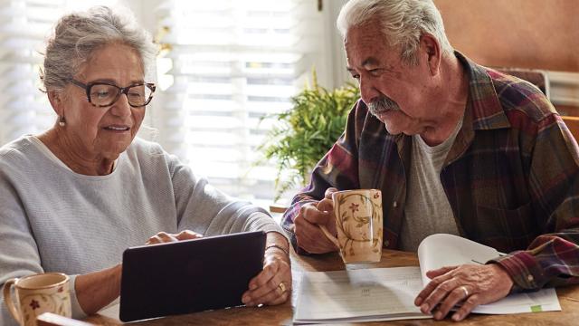 A couple looks at a tablet over coffee at their table. 
