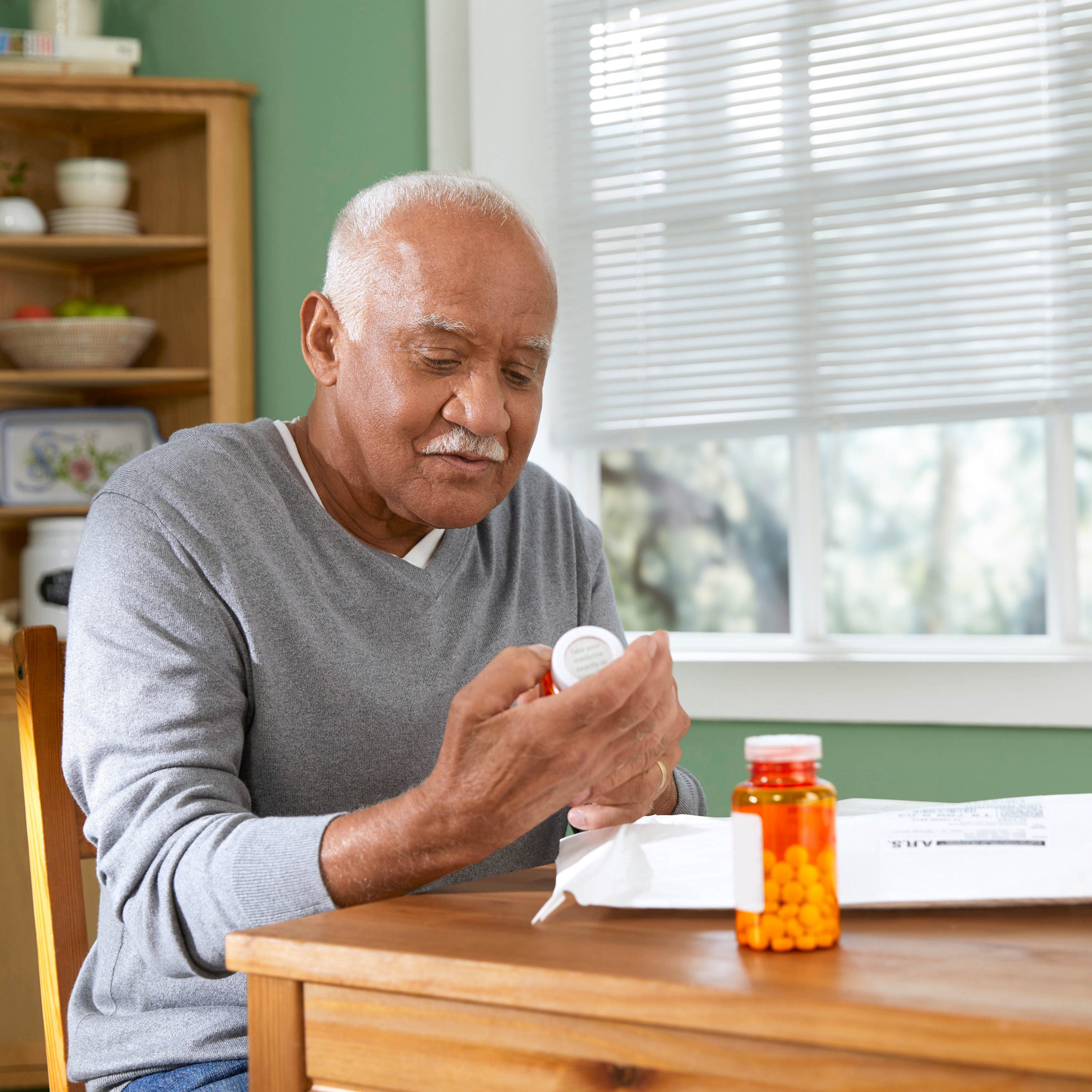 Male member sitting in dining room reviews medication from non-cold pack