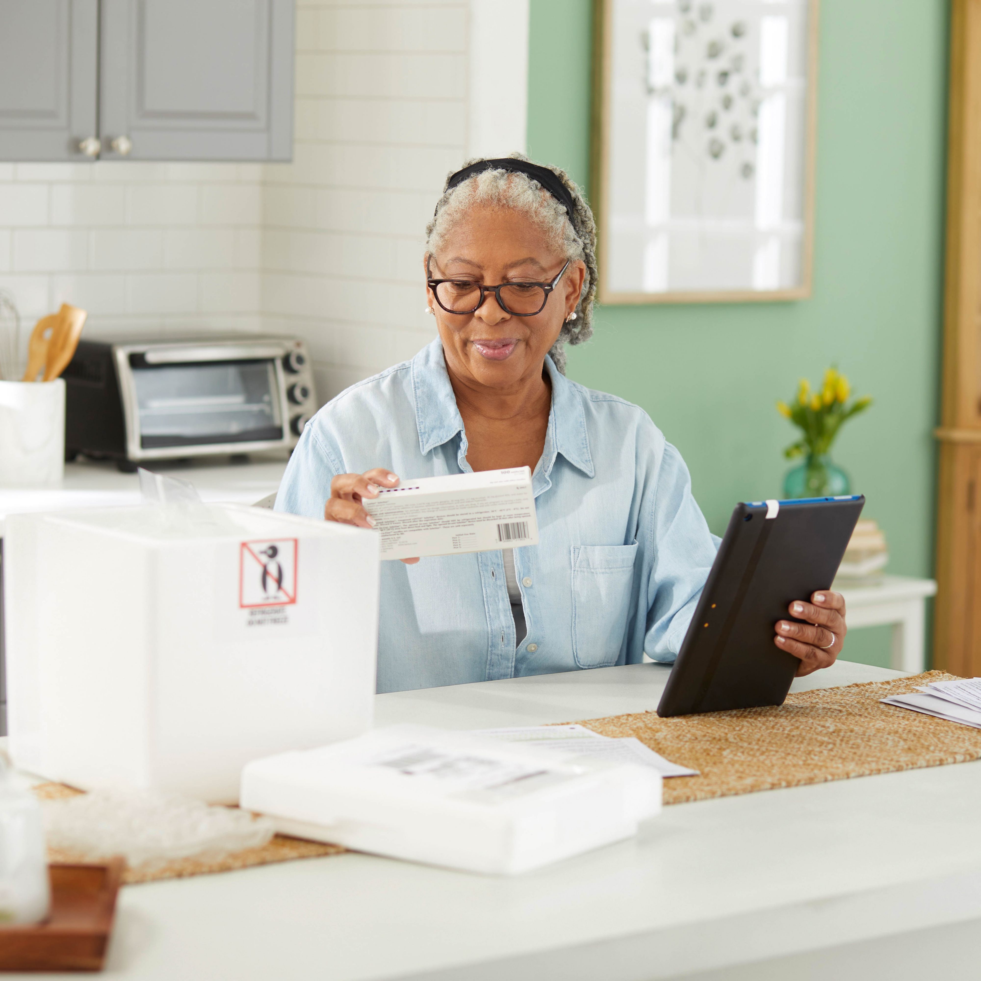 Member in her kitchen opens cold pack and reviews medication