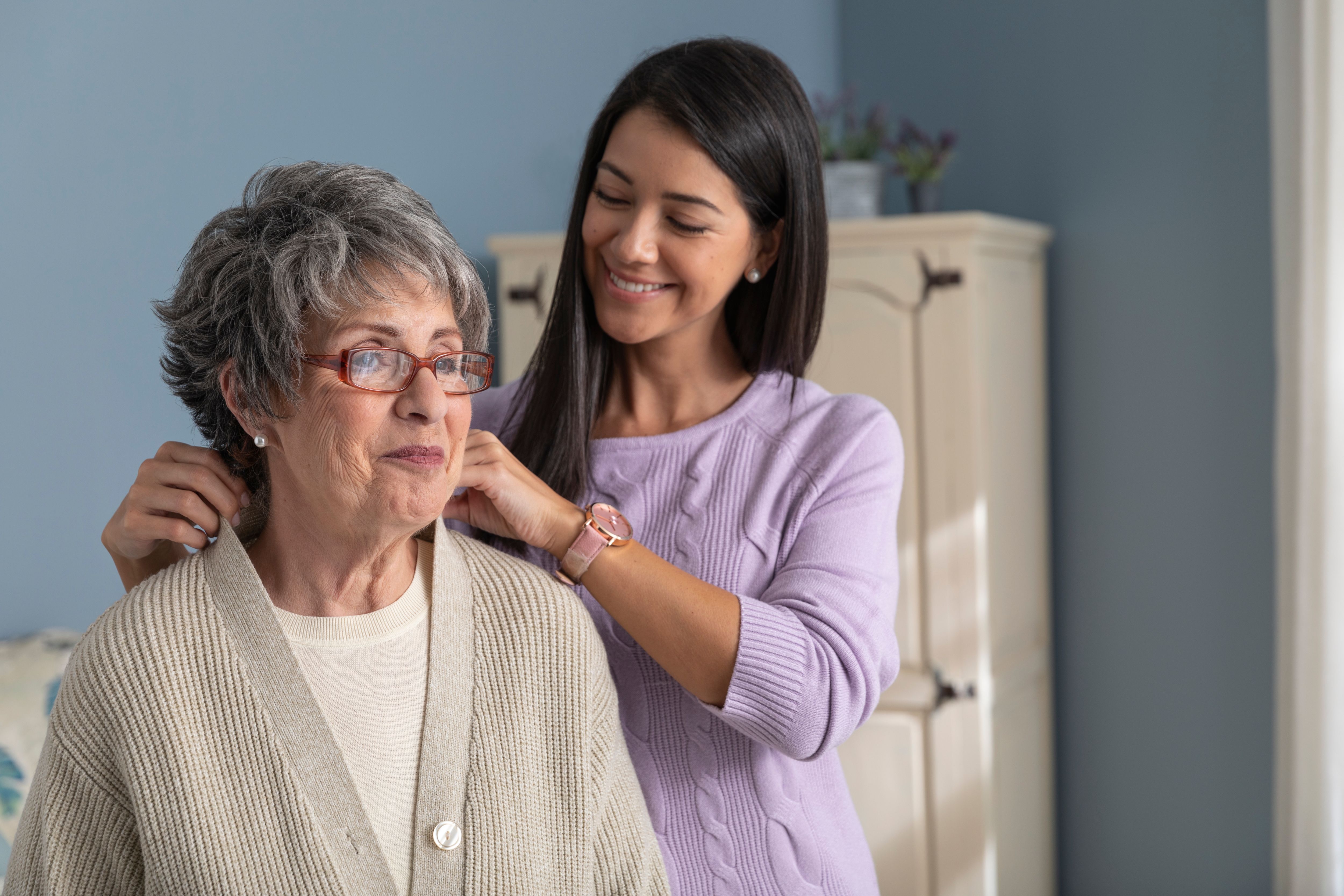 Caregiver helps member put on a sweater