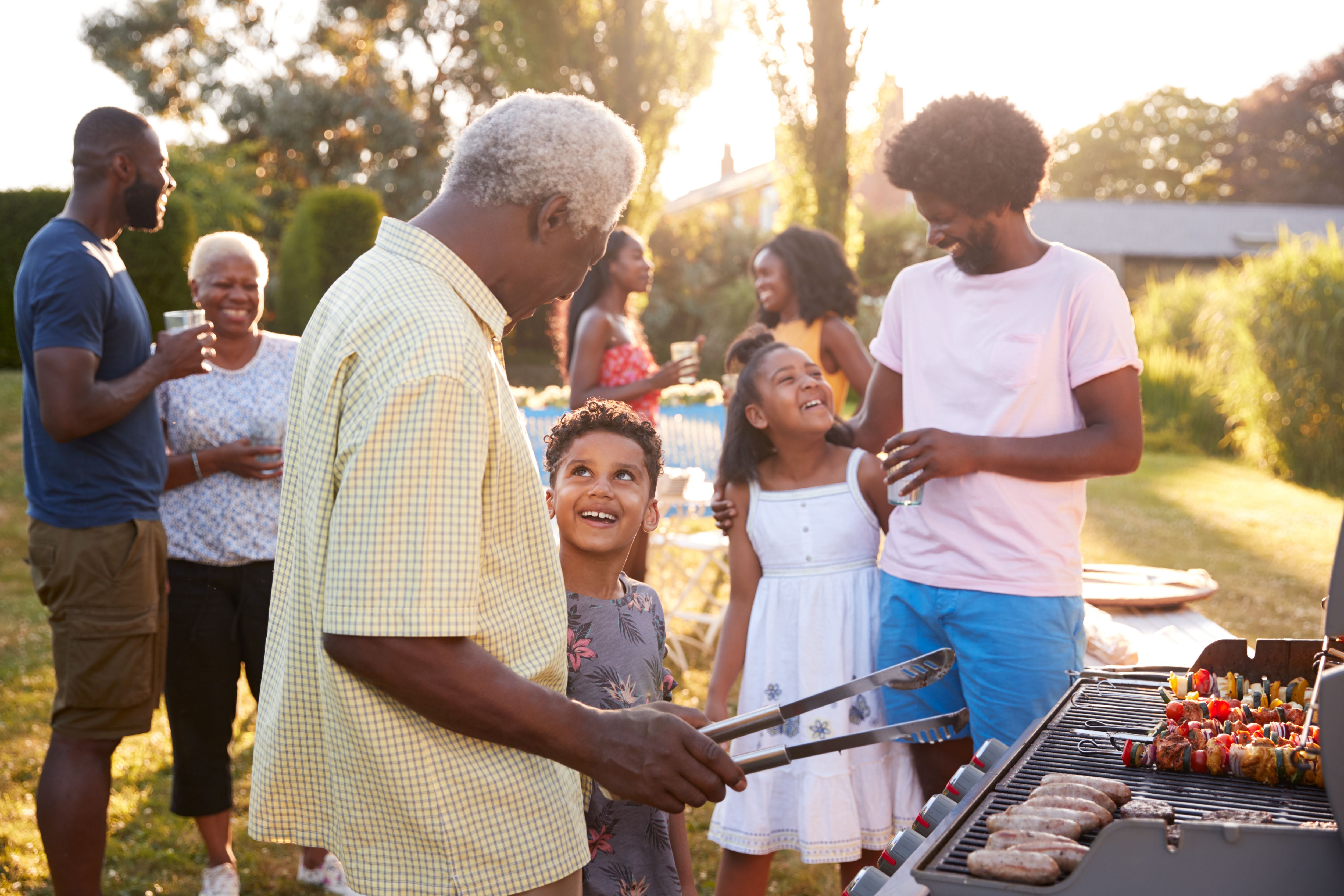 Grandad and grandson talk by the grill at a family barbecue