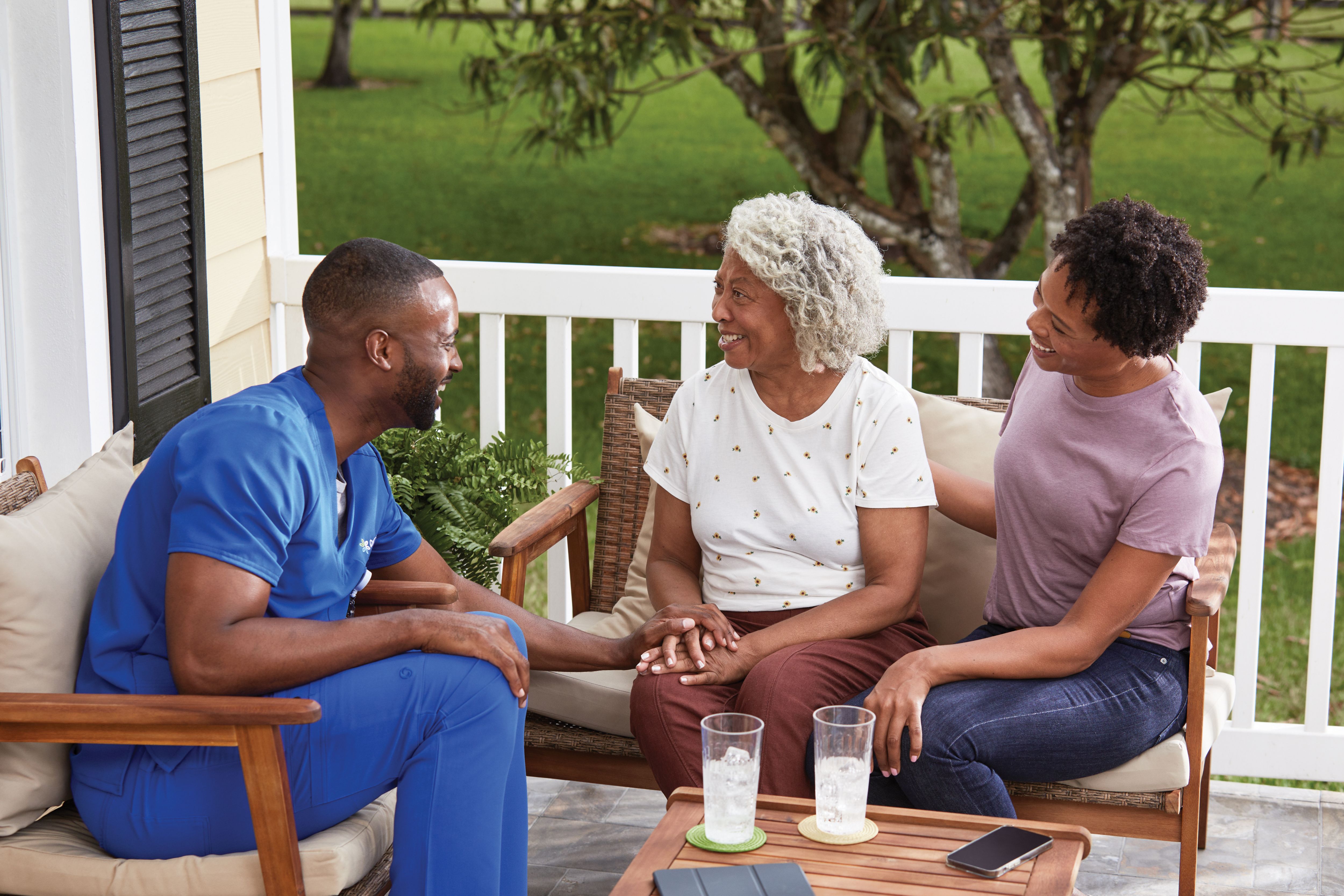 Member and registered nurse sitting on a porch bench in the springtime