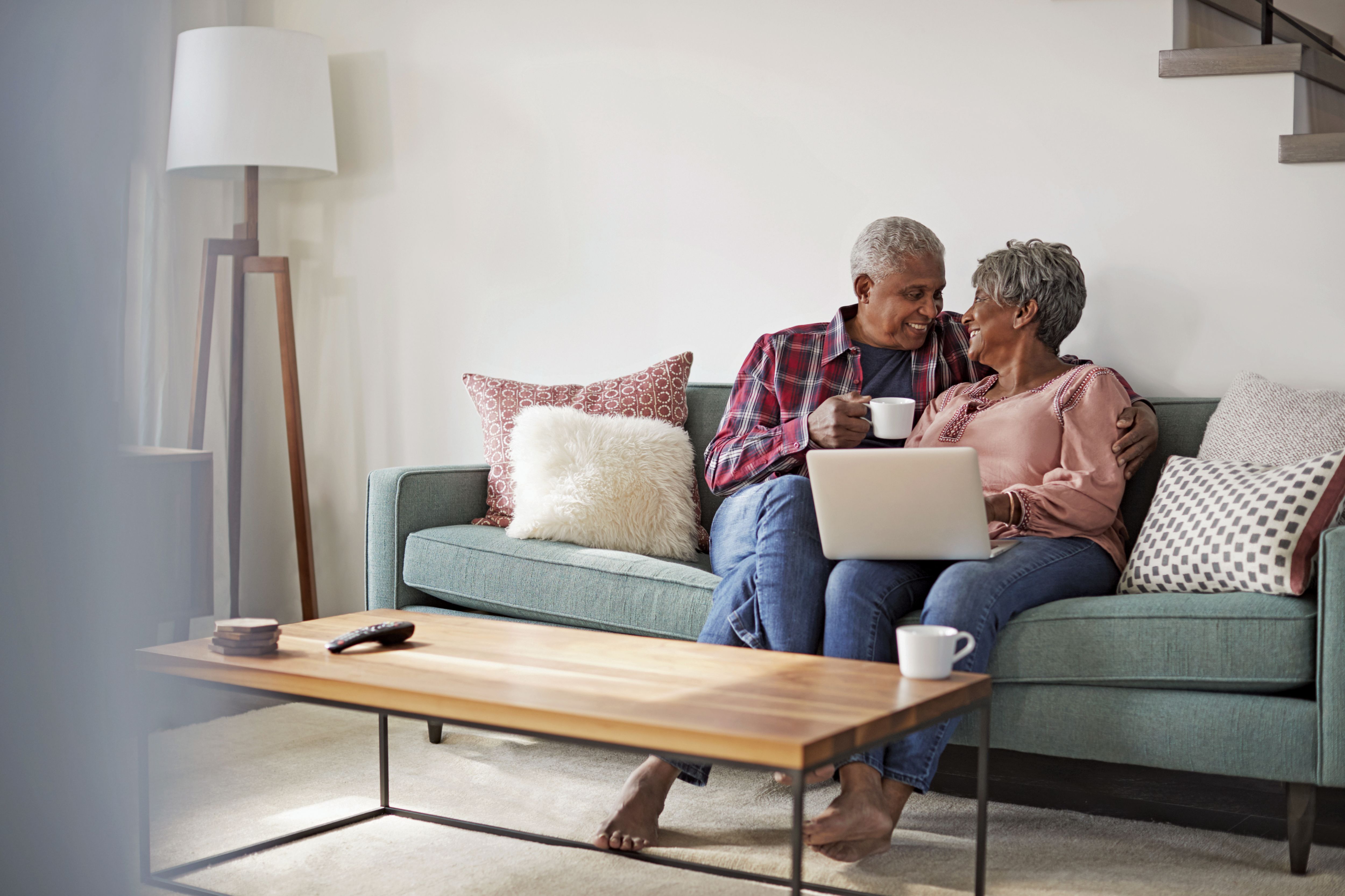 Senior Couple Sitting On Sofa At Home Using Laptop To Shop Online