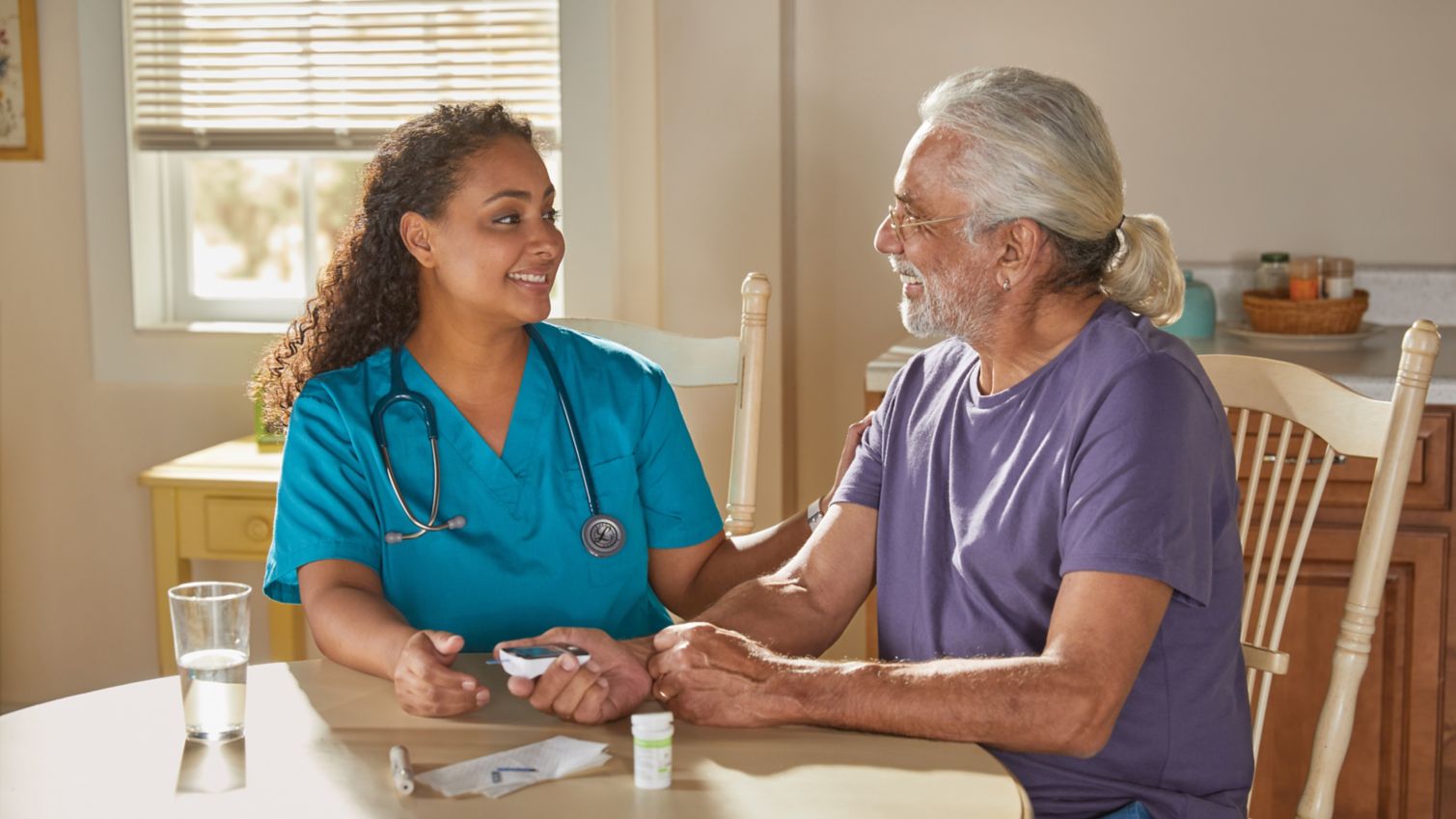 A  female caretaker assists a man test his glucose