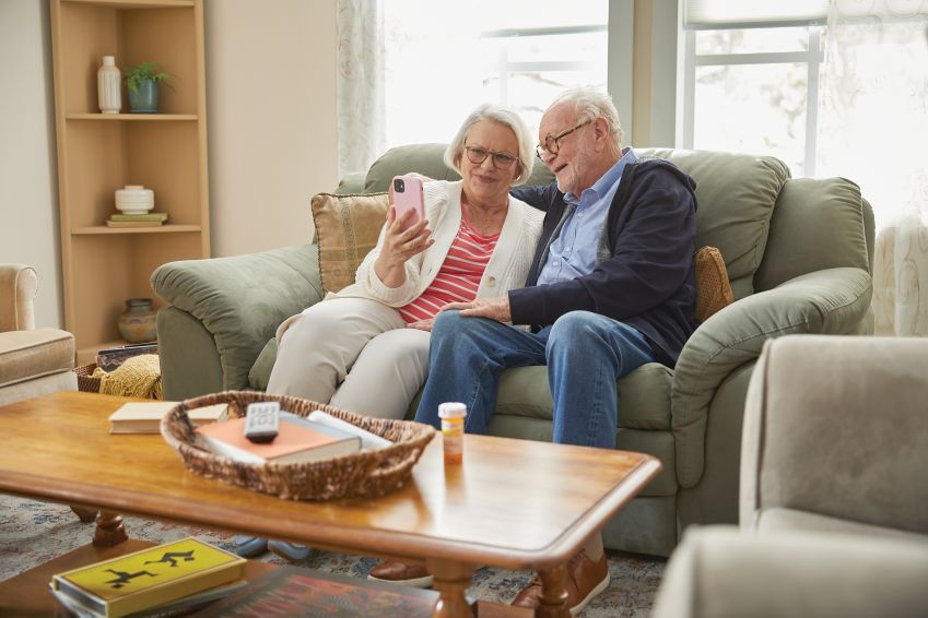 A couple reads from a smartphone in their living room. 