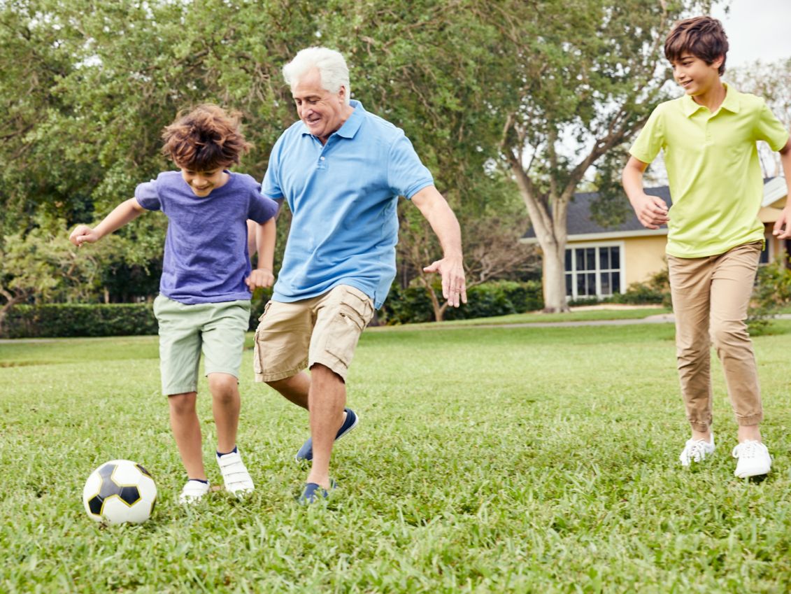 Grandfather plays soccer with grandson.