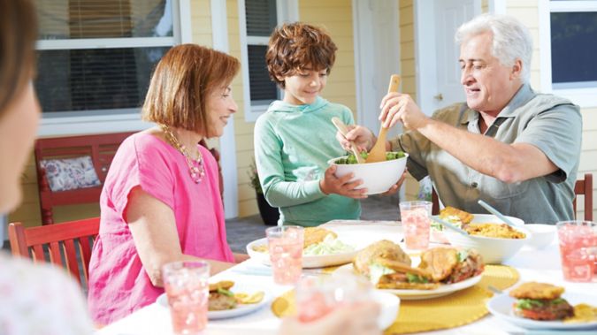 Senior couple enjoying a meal with their family together at home outside on the patio.