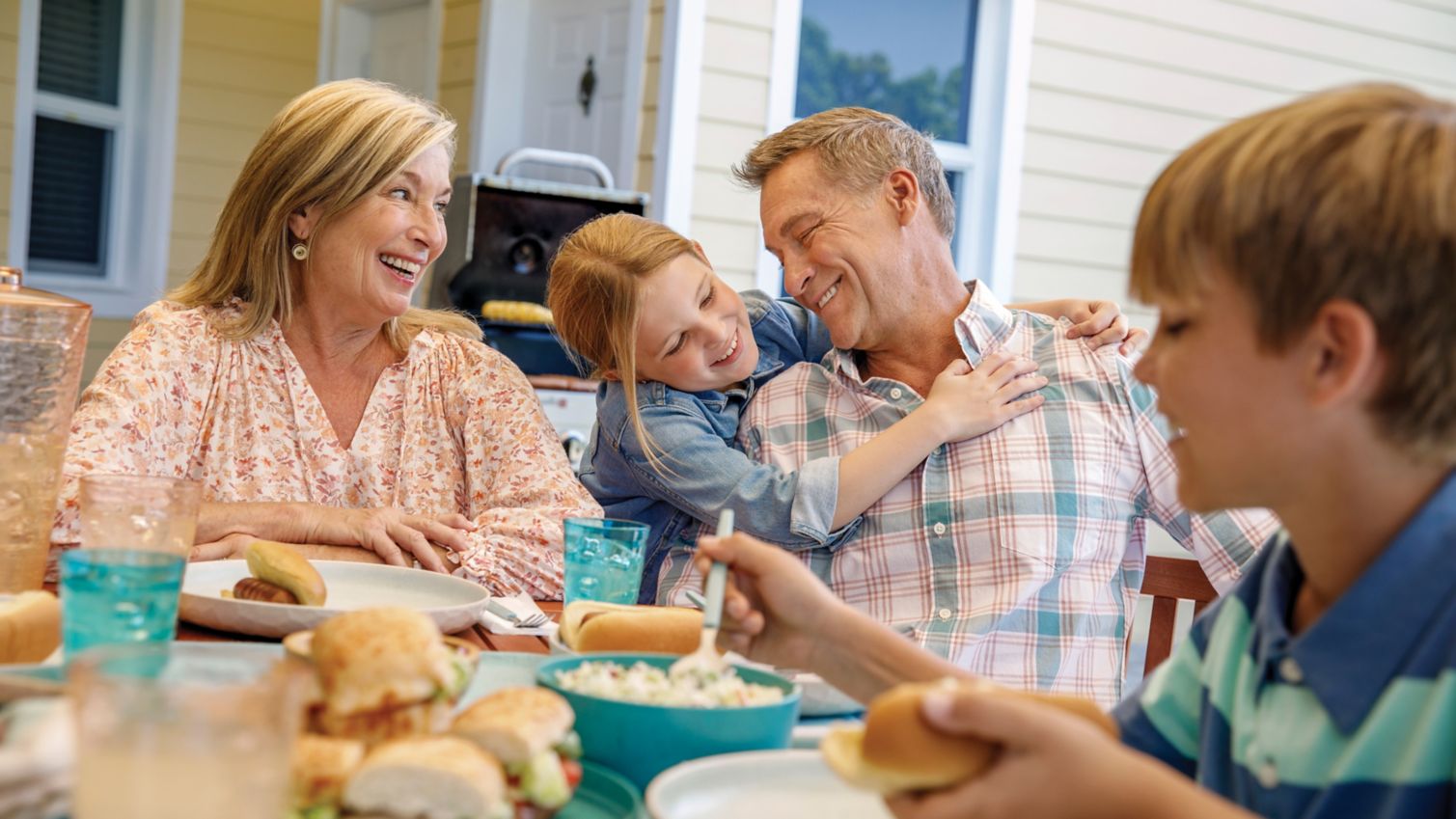 A couple shares lunch with their grandchildren on their patio. 