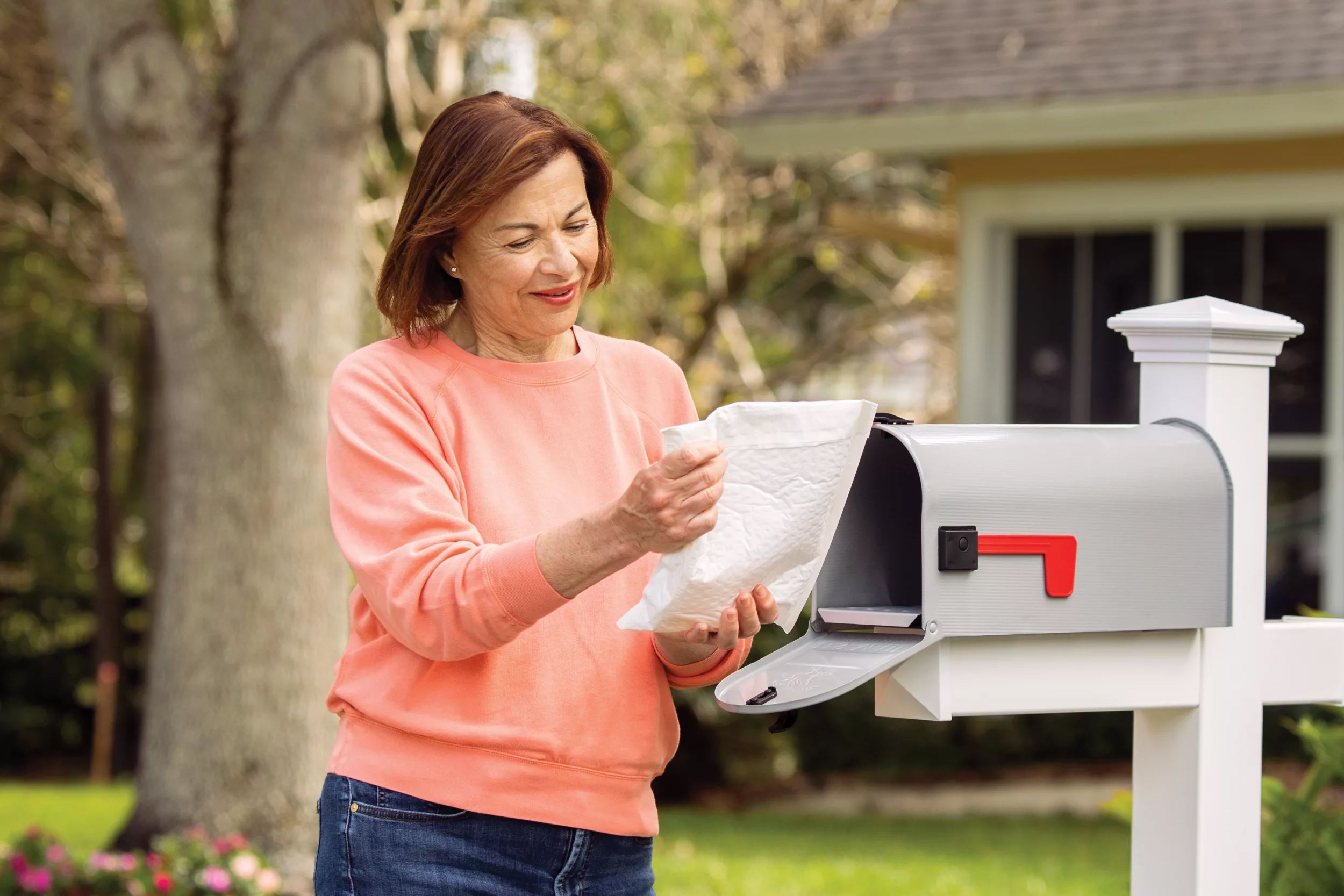 Senior woman at mailbox looking at RX prescription package