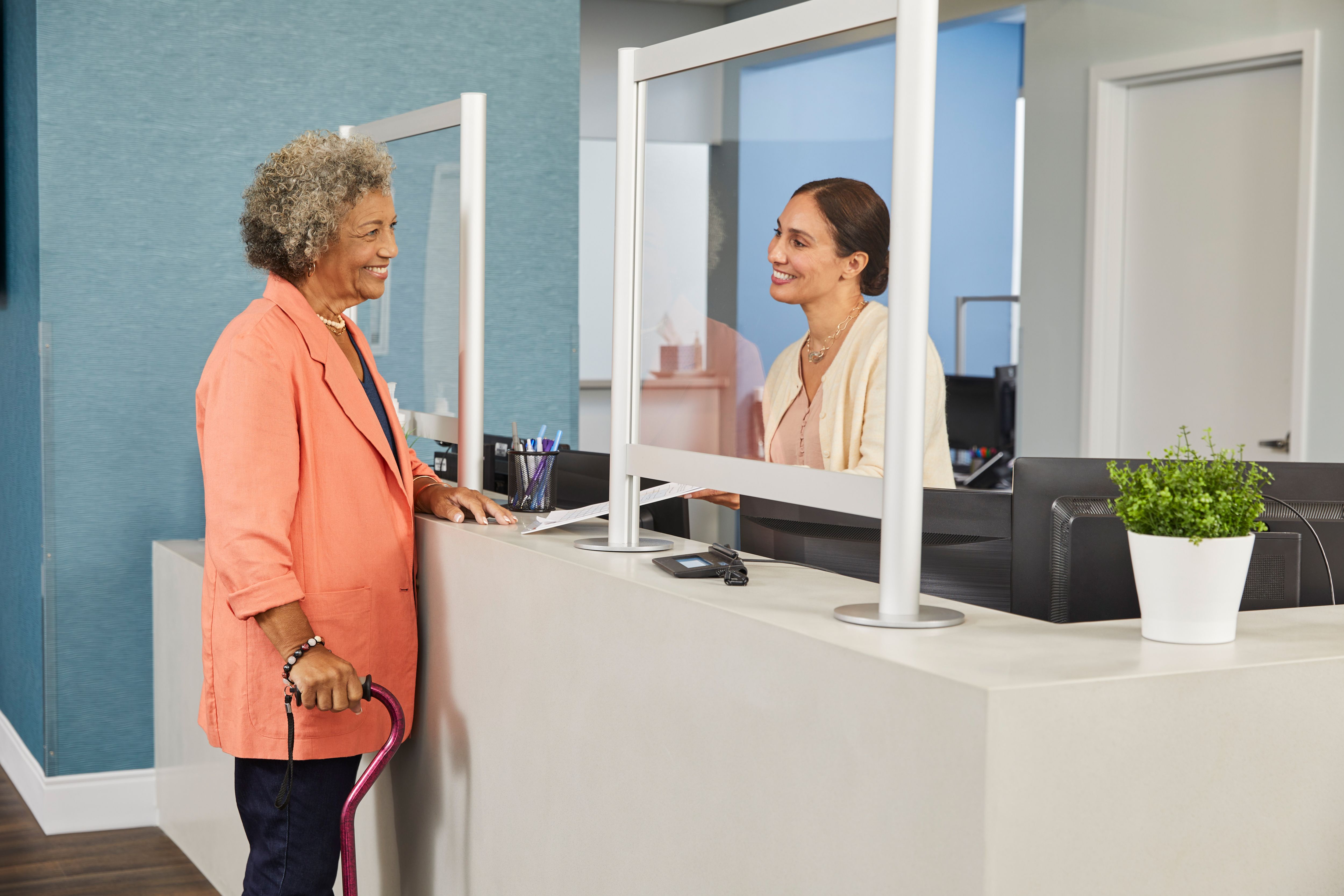 A woman smiles while speaking to a receptionist at an appointment. 