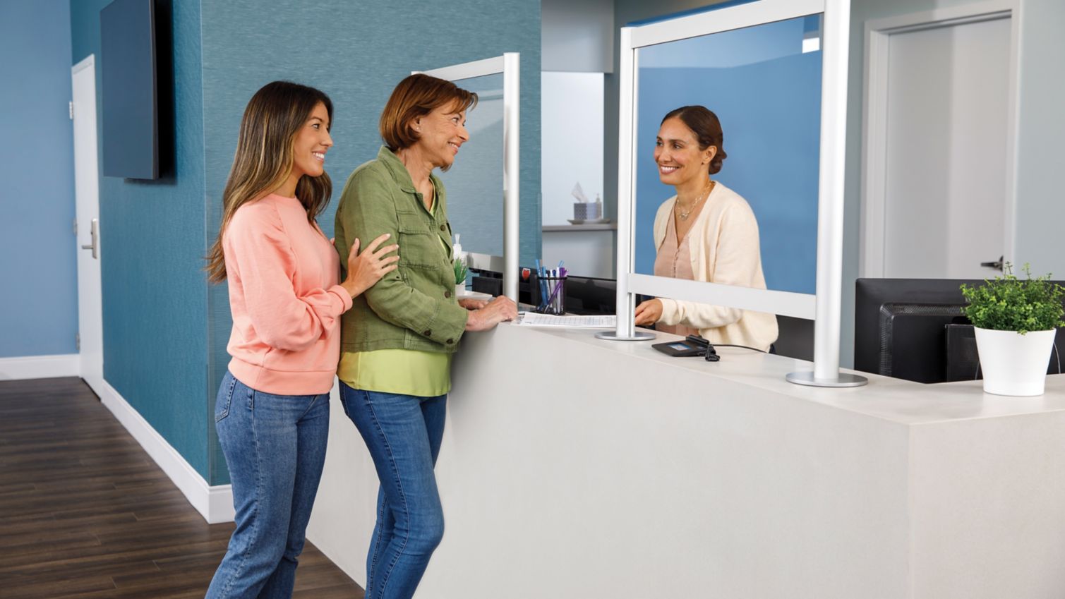 A woman and her daughter check in at a desk for an appointment. 