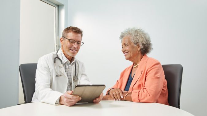 A woman meets with her provider while they review information on a tablet.