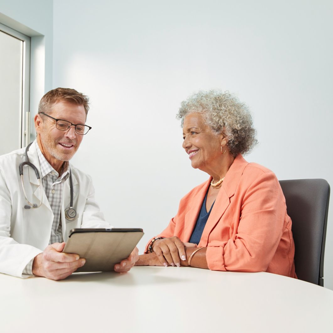 A woman meets with her provider while they review information on a tablet.