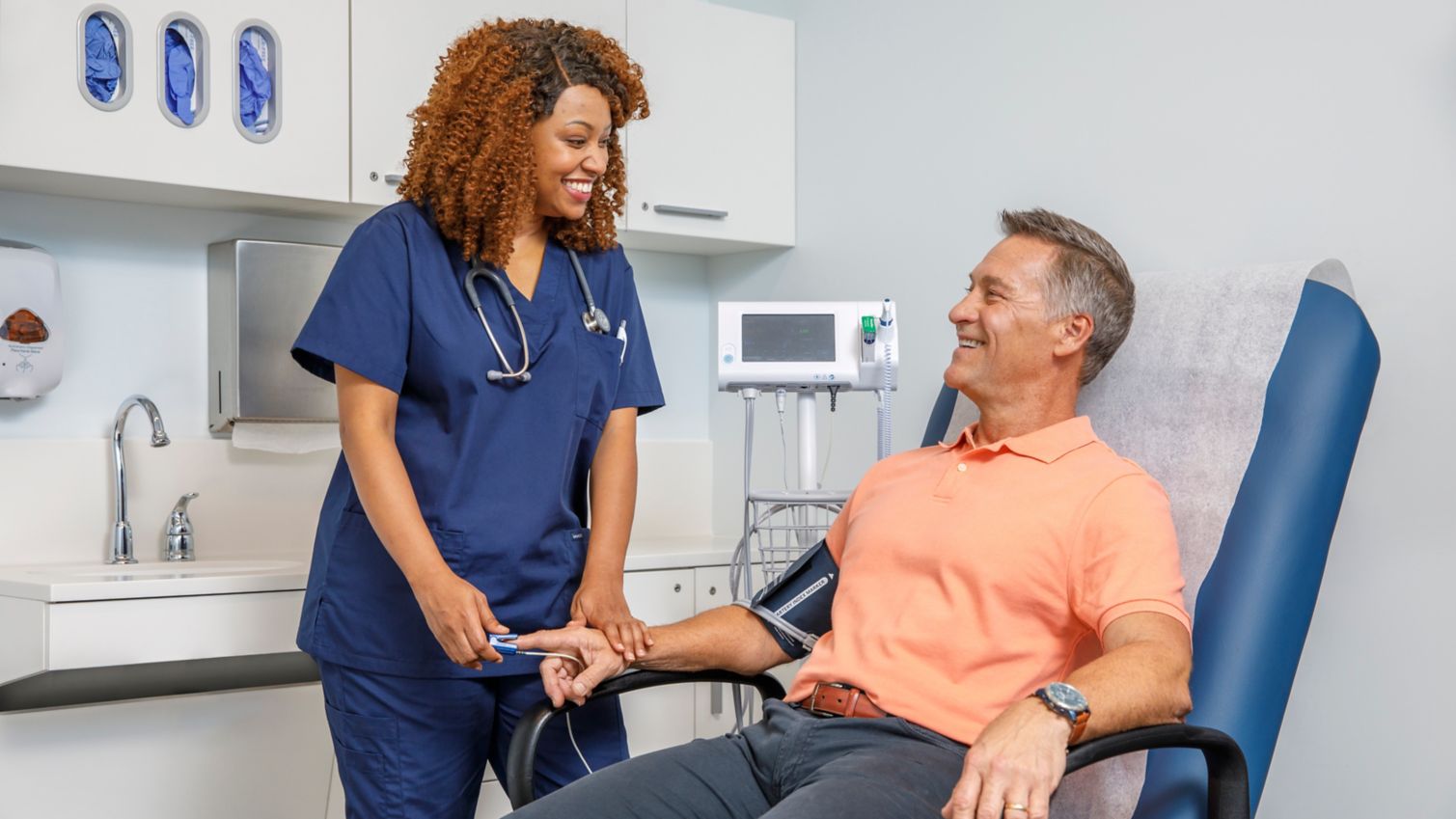 A doctor checks a man’s heartbeat with a stethoscope in an examination room.