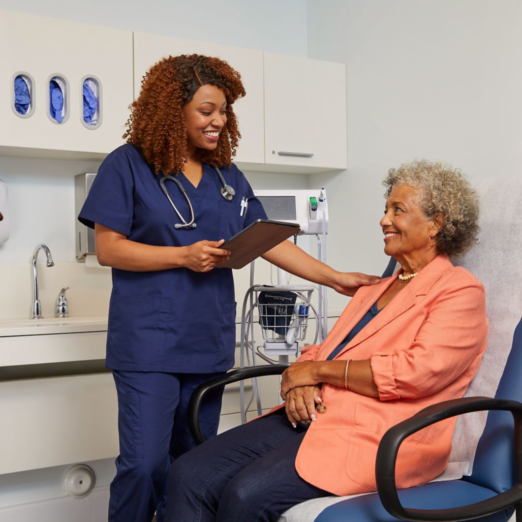 Woman doctor speaking to patient sitting in chair.