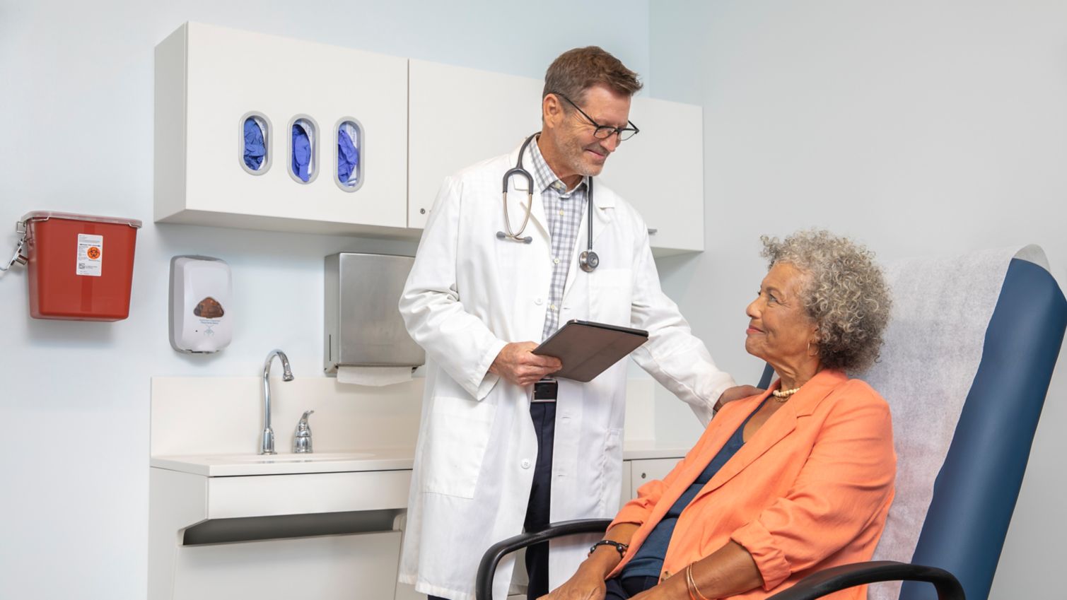 A woman meets with her doctor in an exam room. 