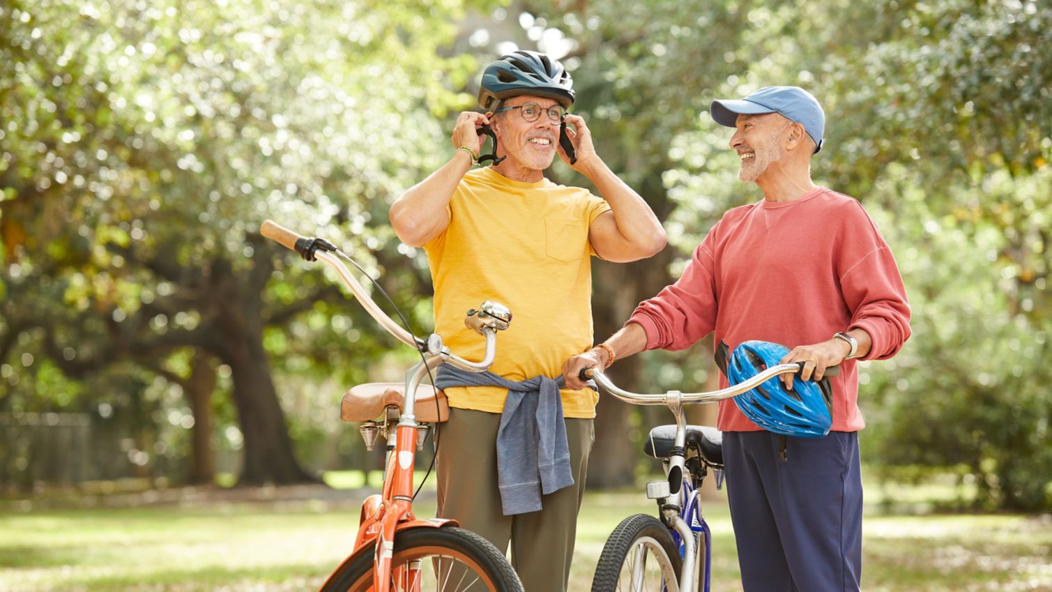 Two men standing next to bikes in a park.