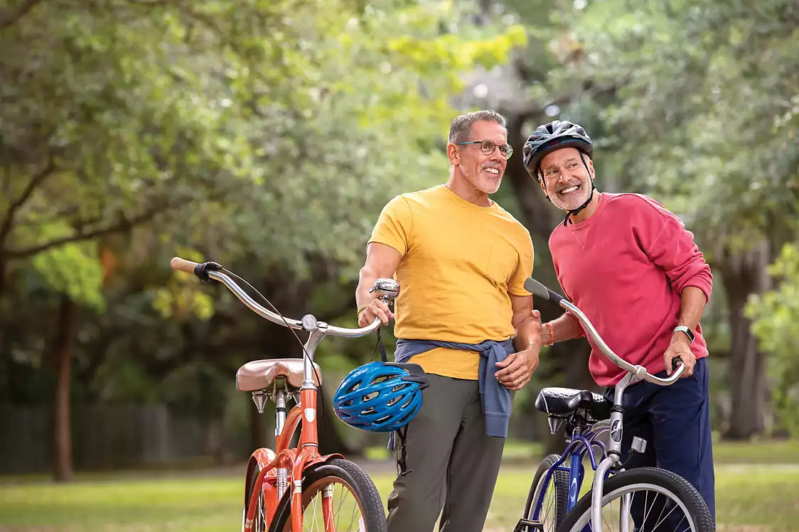 Senior male couple are riding bikes together in the park