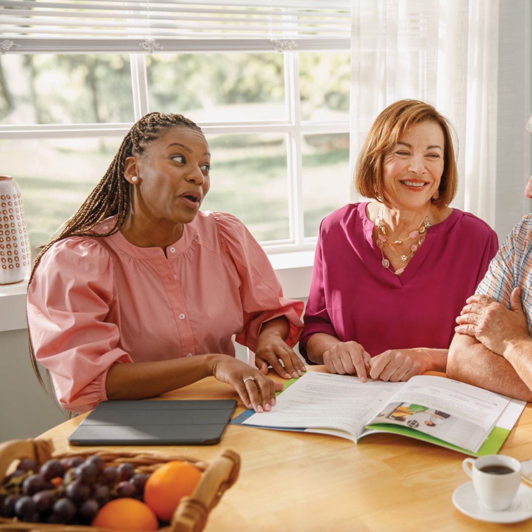 An agent meets with a couple in their home and reviews documents. 