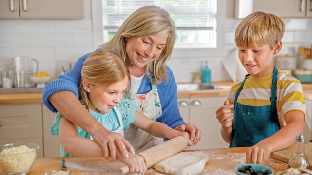 A woman bakes with her grandkids. 