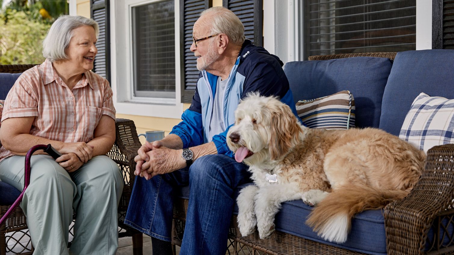 Senior couple sitting on porch with dog.