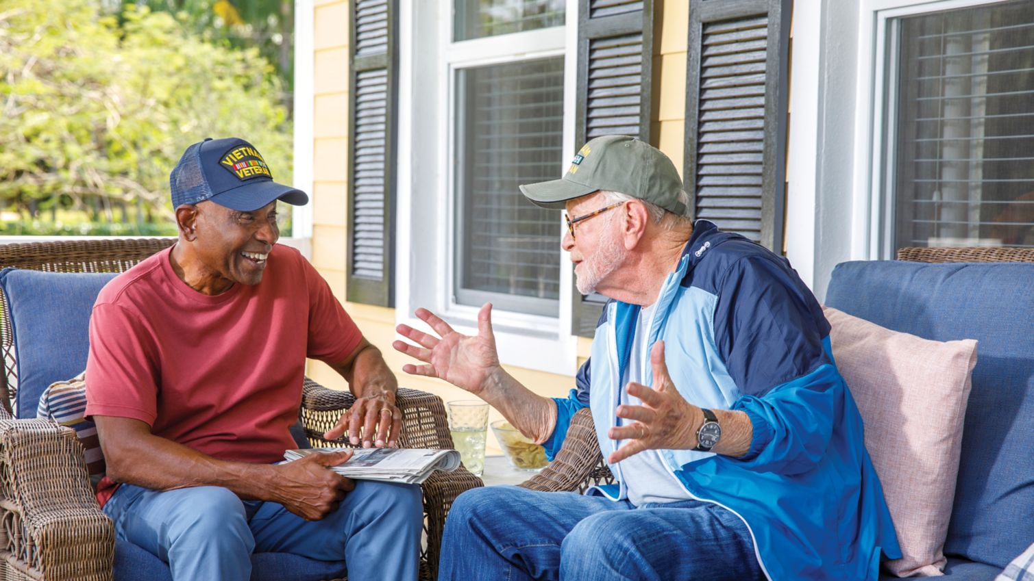 2 older male U.S. military veterans talking on a porch.