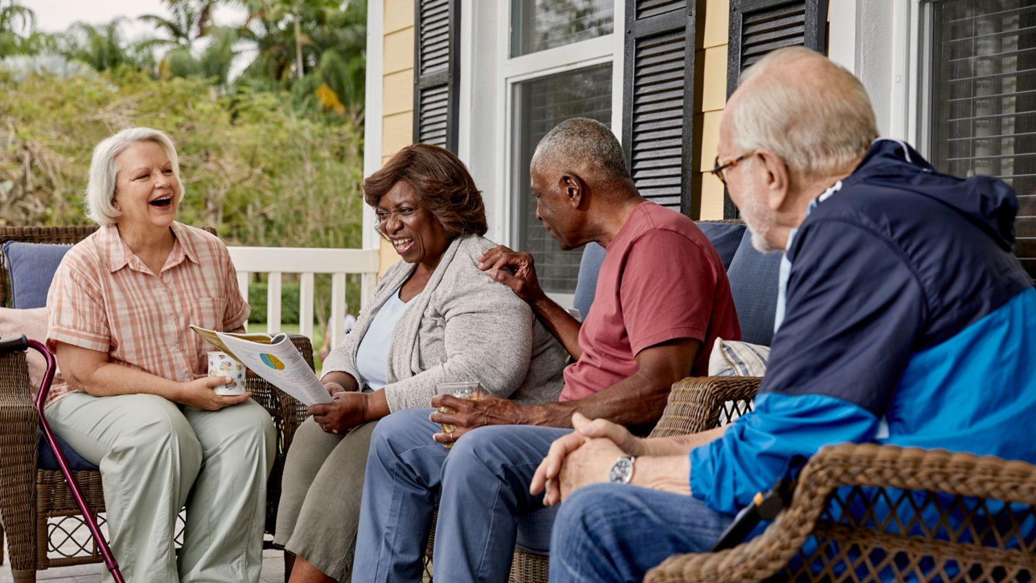 A group of friends laugh together on a porch. 