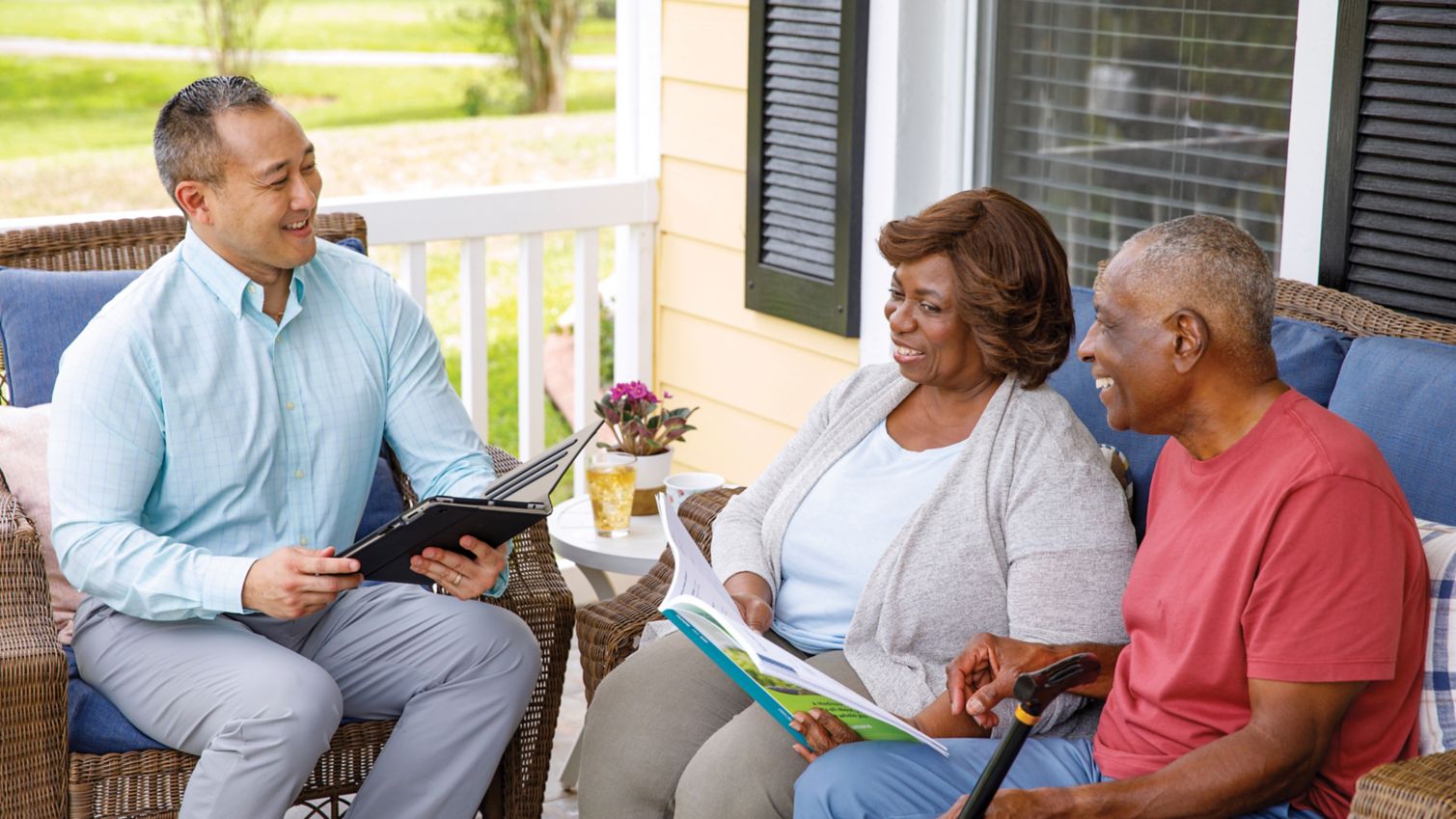 A couple meets with an agent on their porch. 