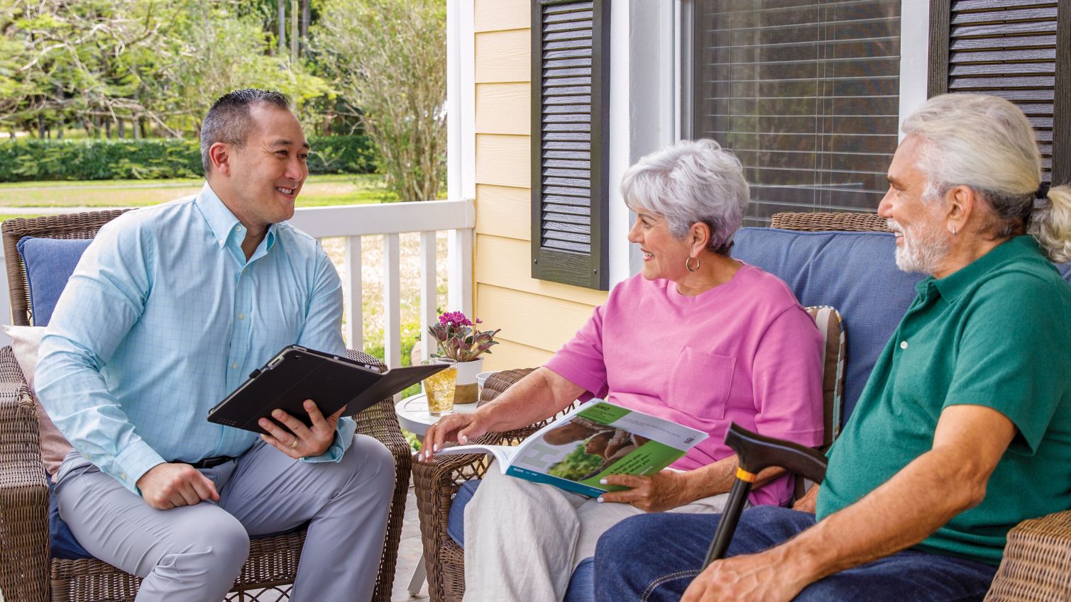 Insurance agent speaking with couple on front porch.