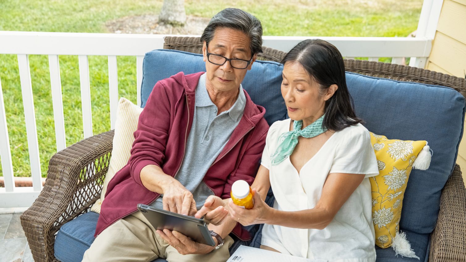 Couple reading tablet and prescription bottle label together.