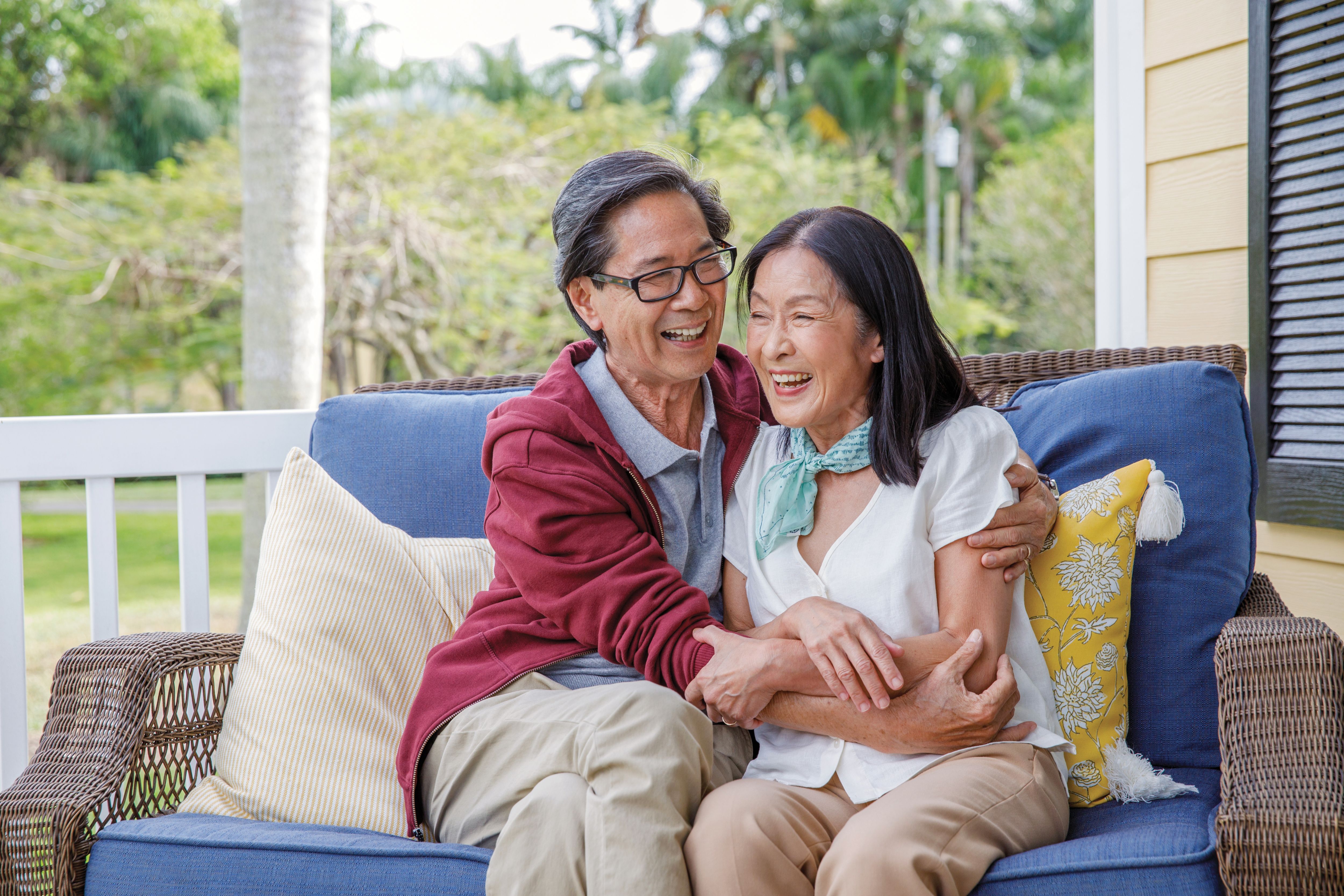 Senior couple sitting on porch couch embracing and smiling