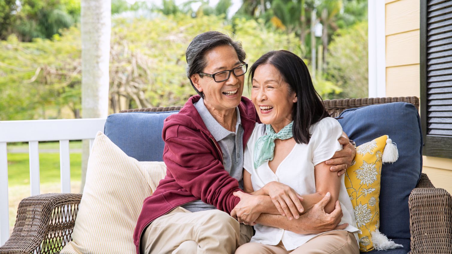 Senior couple sitting together on porch reviewing tablet and medications.