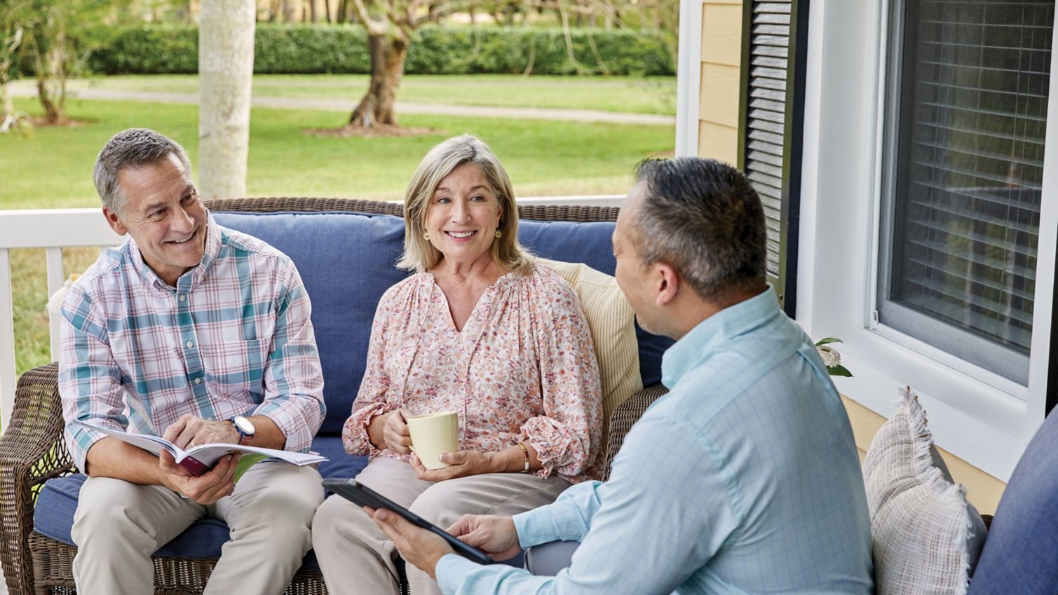 A couple meets with an agent on their porch. 