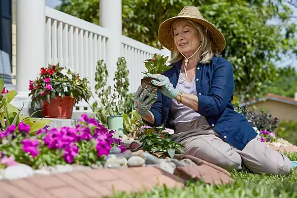 Senior woman in gardening attire sitting in her yard, planting and gardening