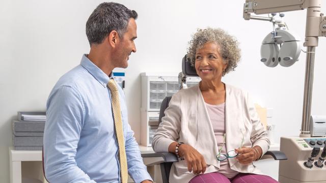 Male optometrist speaks to female patient in exam room.