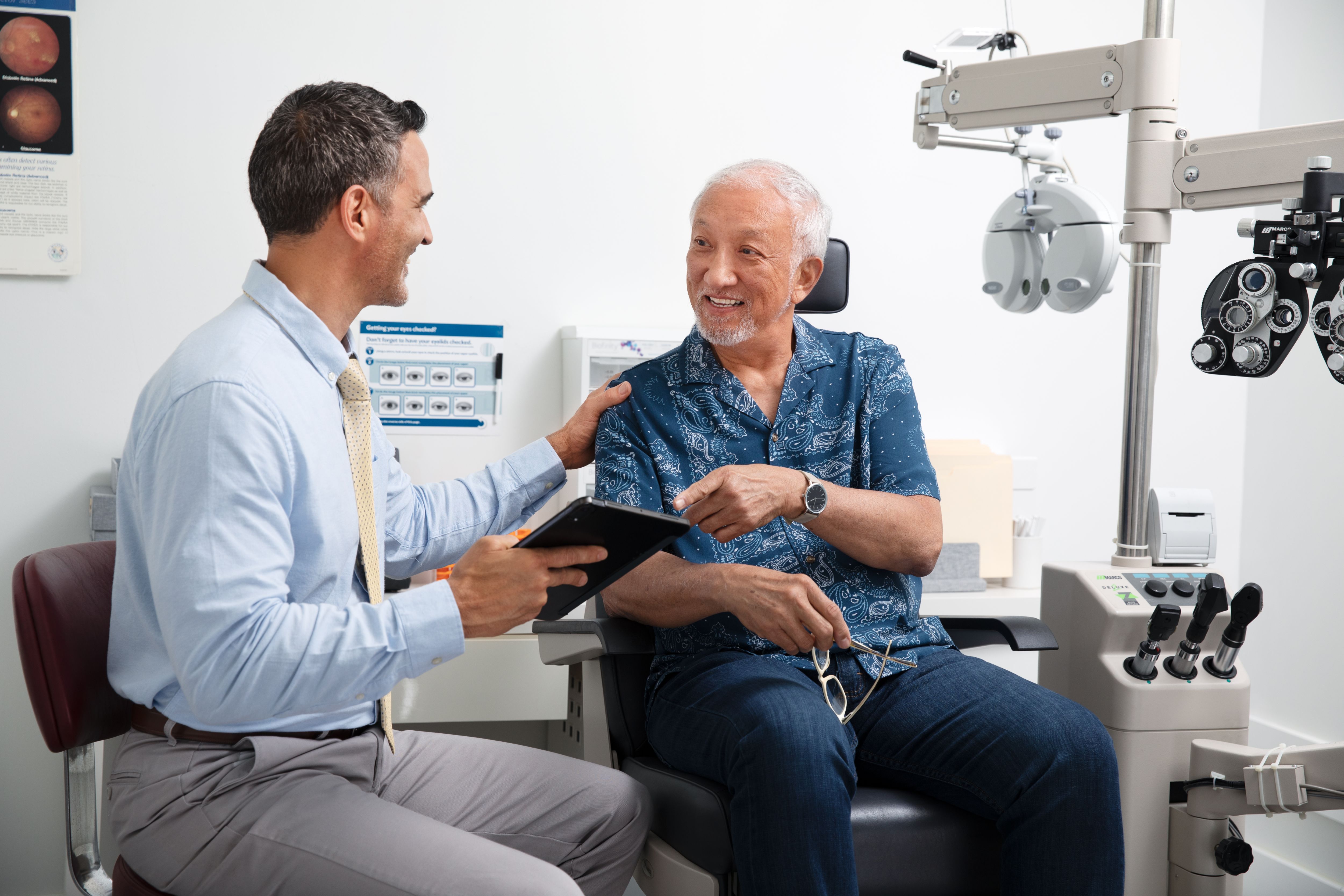 Man at optometrist's office getting consultation talking to doctor with tablet 