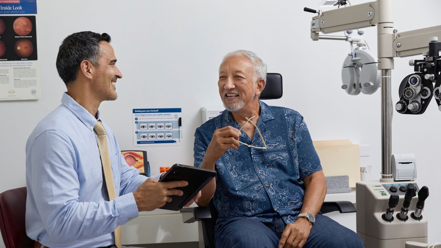 A man smiles while speaking with his eye doctor in an exam chair.