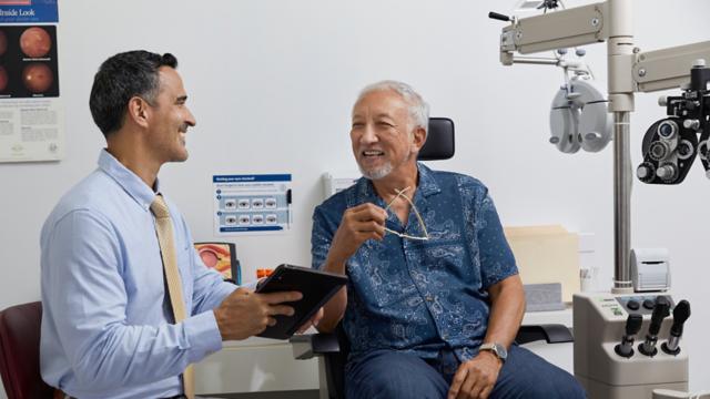 A man smiles while talking to his eye doctor. 
