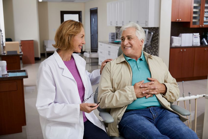 A man smiles while talking with his dentist.