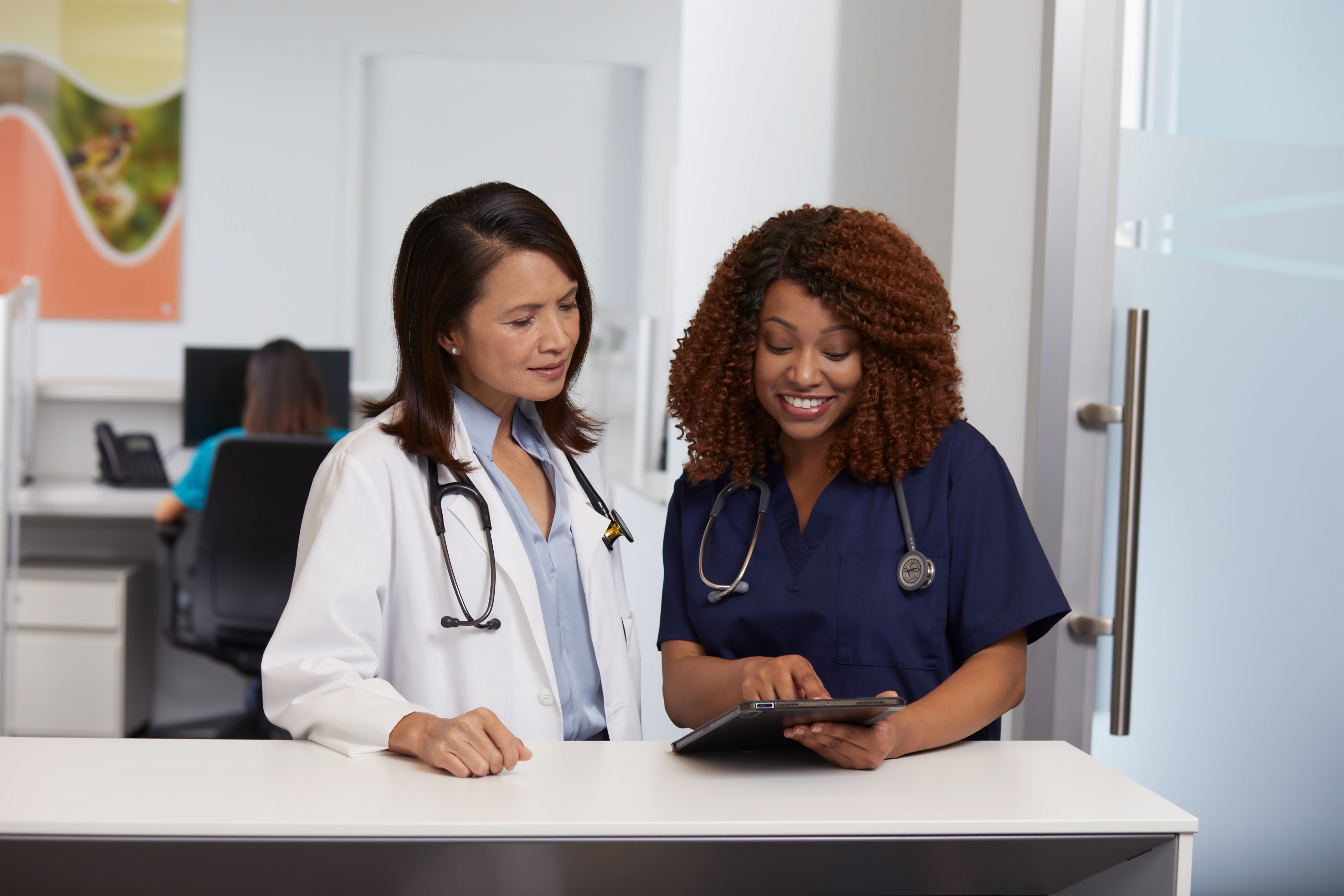 Doctor and nurse are talking together and looking at tablet
